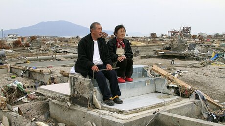 Japanisches Paar sitzt in den Trümmern ihres Hauses / © Kimimasa Mayama (dpa)