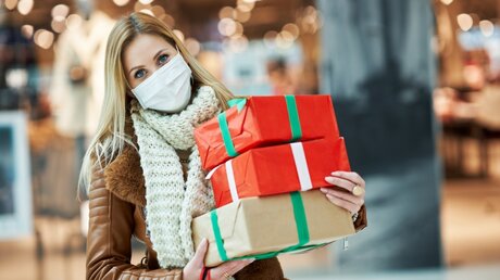 Frau mit Mundschutz und Weihnachtsgeschenken beim Einkaufen / © Kamil Macniak (shutterstock)