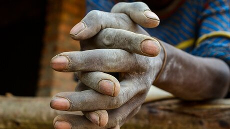 Gefaltete Hände eines Minenarbeiters im Kongo  / © Harald Oppitz (KNA)
