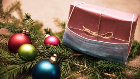 Geschenk und Mundschutz mit Weihnachtsdekoration / © Miriam Doerr Martin Frommherz (shutterstock)
