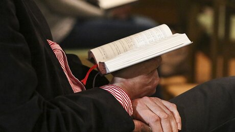 Gottesdienstbesucher hält ein Gotteslob in den Händen / © Jörg Loeffke (KNA)