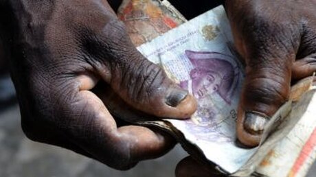 Haiti: Ein Mann zählt Geld (KNA)
