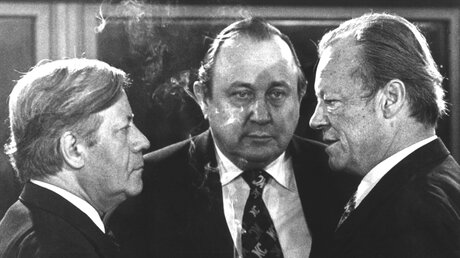 Vor Beginn der Sitzung im Bonner Bundeskanzleramt unterhalten sich am 13.12.1976 (l-r): Bundeskanzler Helmut Schmidt (SPD), Bundesaußenminister Hans-Dietrich Genscher (FDP) und der SPD-Vorsitzende Willy Brandt.  (dpa)