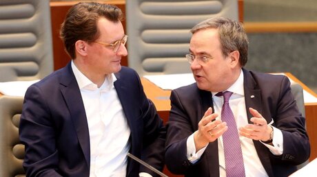 Hendrik Wüst spricht im NRW-Landtag mit Armin Laschet / ©  Roland Weihrauch (dpa)