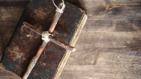 Holzkreuz auf einem alten Buch / © alexkich (shutterstock)