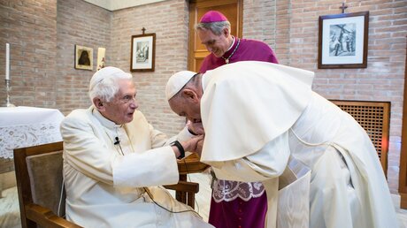 Papst Franziskus küsst die Hand des emeritierten Papstes Benedikt XVI. (l.) (Archiv) / © Vatican Media/Romano Siciliani (KNA)