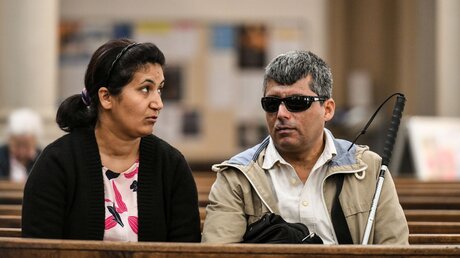 Ein blinder Mann sitzt mit seiner Frau in einer Kirchenbank / © Harald Oppitz (KNA)