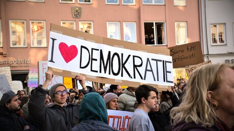 Ein Schild mit der Aufschrift Ich liebe Demokratie bei einer Demonstration gegen rechts am 3. Februar 2024 in Augsburg. / © Christopher Beschnitt (KNA)