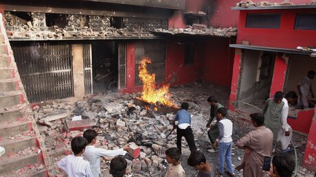 Jugendliche stehen vor einer Kirche, die beschädigt und niedergebrannt wurde / © Muhammad Shafqat (dpa)