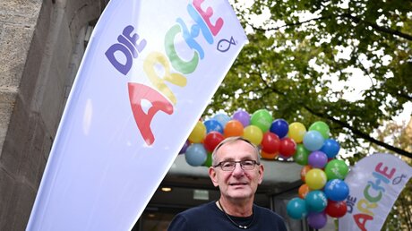 Bernd Siggelkow, der Gründer des Kinderhilfswerks "Arche", steht bei der Einweihung einer "Arche"-Einrichtung vor dem Gebäude an einem Logo. / © Bernd Weißbrod (dpa)