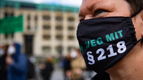 Demonstrantin mit der Schriftzug Weg mit §218 auf einer Maske / © Paul Zinken (dpa)