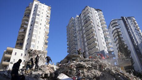Notfallteams suchen im türkischen Adana nach Menschen in den Trümmern eines zerstörten Gebäudes. Mehr als 13 Millionen Menschen in der Türkei sind nach Einschätzung der Regierung von der Erdbebenkatastrophe betroffen. / © Foto: Hussein Malla (KNA)
