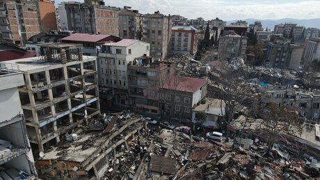 Diese Luftaufnahme zeigt eingestürzte Gebäude in Kahramanmaras in der Türkei. Rettungskräfte suchen weiterhin nach Überlebenden in den Trümmern tausender Gebäude, die durch ein starkes Erdbeben und mehrere Nachbeben, die die Osttürkei und das benachbarte Syrien erschütterten, eingestürzt waren. / © Mustafa Kaya (dpa)