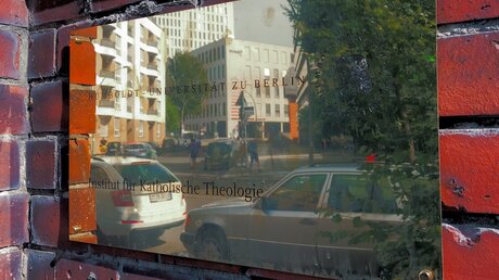 Die Straße spiegelt sich in dem Schild mit der Aufschrift Humboldt-Universität zu Berlin Institut für Katholische Theologie / © Gregor Krumpholz (KNA)