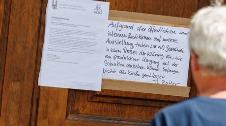 Pressemitteilung und Zettel zur vorübergehenden Schließung der Ausstellung "Jesus liebt" an der Nürnberger Kirche St. Egidien  / © Daniel Karmann (dpa)
