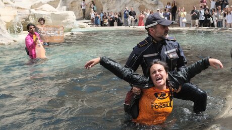 Klimaaktivisten der Letzten Generation werden von Polizisten aus dem Wasser des Trevi-Brunnen geleitet. / © Mauro Scrobogna/LaPresse (dpa)