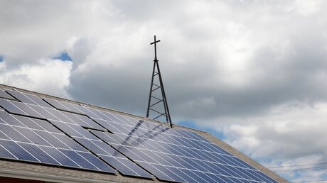 Ein Metallkreuz auf einem Dach mit Solarpanels / © rustycanuck (shutterstock)