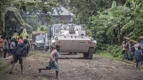 Demokratische Republik Kongo, Kibumba: Einige Menschen stehen an einer Stra&szlig;e und beobachten Monusco-Blauhelme in einem milit&auml;rischen Fahrzeug.  / &copy; Moses Sawasawa/AP (dpa)