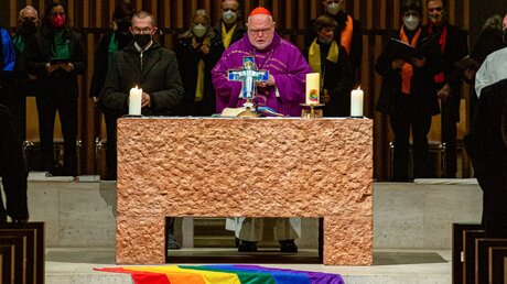 Kardinal Reinhard Marx steht am Altar während des Gottesdienstes zum 20-jährigen Bestehen von Queer-Gottesdiensten in der Kirche Sankt Paul am 13. März 2022 in München. Eine Regenbogenfahne liegt auf den Altarstufen. / © Robert Kiderle (KNA)