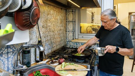 Chefkoch Mosche Basson bereitet ein traditionelles Essen mit Mariendisteln und Khubeza zu am 26. Februar 2024 in seiner Wohnung in Modi'in (Israel). / © 	Andrea Krogmann (KNA)