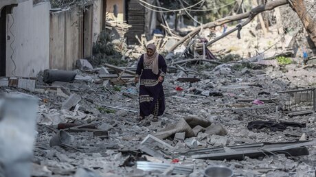 Eine Frau geht nach einem israelischen Luftangriff durch Gaza-Stadt / © Mohammed Talatene (dpa)