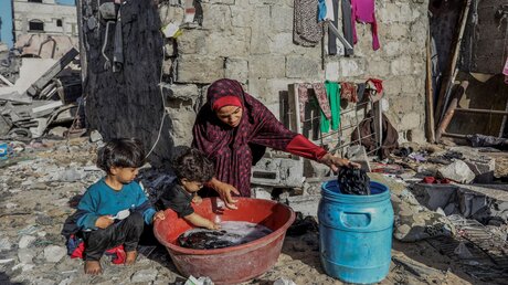 Eine Palästinenserin wäscht ihre Kleidung in ihrem zerstörten Haus nach israelischen Luftangriffen im Lager Shaboura im südlichen Gazastreifen / © Abed Rahim Khatib (dpa)