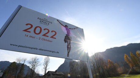 Die Sonne scheint hinter einem Plakat für die Passionsspiele 2022 hervor / © Angelika Warmuth (KNA)