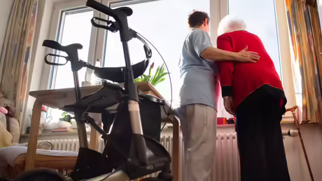 Eine Pflegerin und eine Heimbewohnerin schauen zusammen aus einem Fenster im Wohnbereich des Pflegeheims / &copy; Tom Weller (dpa)