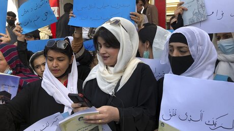 Kabul: Frauen halten bei einer Demonstration im März 2022 Transparente und Schilder hoch, während sie gegen die Einschränkung der Frauenrechte durch die militant-islamistischen Taliban protestieren. / © Mohammed Shoaib Amin (dpa)