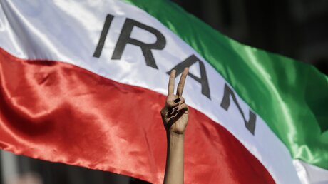  Demonstrantin zeigt das Victory-Zeichen vor einer iranischen Fahne / © Cecilia Fabiano (dpa)