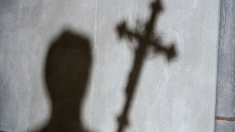 Schatten eines Mannes mit einem Kreuz in der Hand  / © Harald Oppitz (KNA)