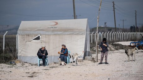 Vor einem Zelt am Rande eines Containerdorfes in der Erdbebenregion Südtürkei/Nordsyrien / © Boris Roessler (dpa)