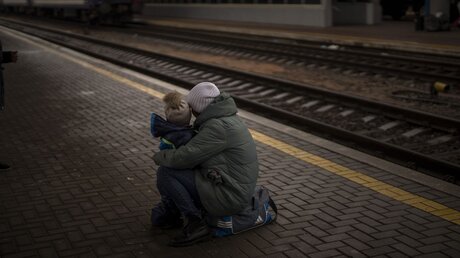 Ukraine, Kiew: Eine Frau und ihr Kind schauen auf einen abfahrenden Zug, als sie am Bahnhof von Kiew in der Ukraine zu fliehen versuchen.  / © Emilio Morenatti (dpa)