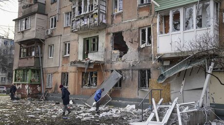 Ukraine: Menschen gehen an einem von Granaten getroffenen Wohnhaus vorüber / © Evgeniy Maloletka (dpa)
