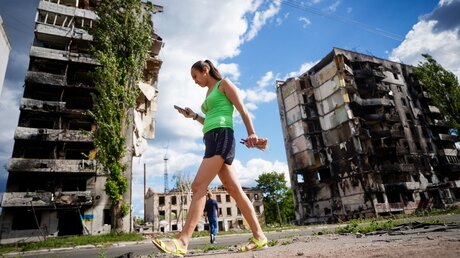 Eine Frau geht an zerstörten Wohnhäusern in Borodjanka vorbei / © Kay Nietfeld (dpa)