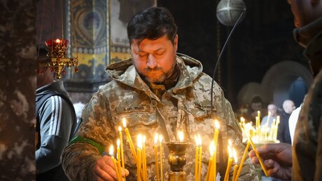  Kiew: Ein ukrainischer Soldat entzündet Kerzen in der Wolodymyski-Kathedrale während der Osterfeierlichkeiten / © Efrem Lukatsky (dpa)