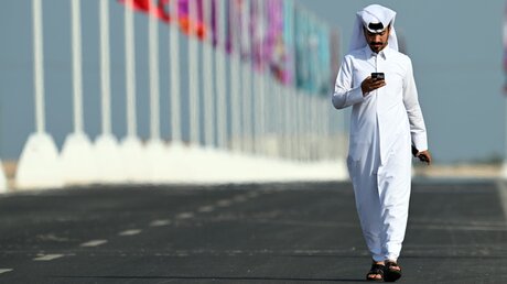 Katar, Doha: Ein Einheimischer schaut auf der Straße auf sein Smartphone / © Federico Gambarini (dpa)