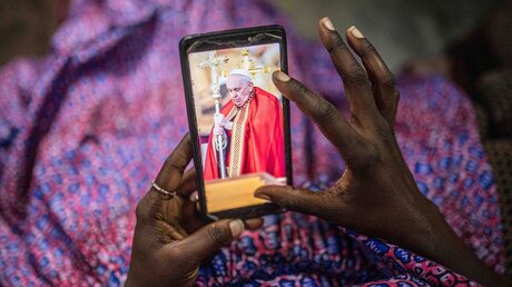 Eine Frau im Kongo betrachtet ein Foto von Papst Franziskus auf ihrem Handy / © Moses Sawasawa (dpa)