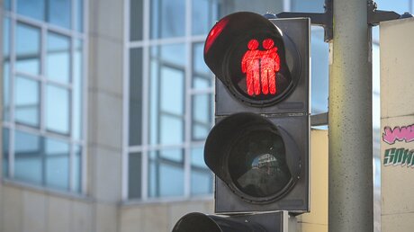 Gleichgeschlechtliches Paar als Ampelzeichen: Ein homosexuelles Pärchen hält sich an der Hand und leuchtet rot an einer Fußgängerampel am 8. Februar 2023 in Bielefeld. / © Harald Oppitz (KNA)