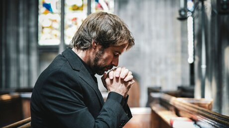 Ein Mann betet in einer Kirche / © Rawpixel.com (shutterstock)