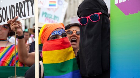 Eine muslimische Frau trägt eine Burka in den Farben der Gay-Pride-Flag (Regenbogenfahne) bei einer Pride-Demonstration am 6. Juli 2019 in London, UK. / © Ink Drop (shutterstock)