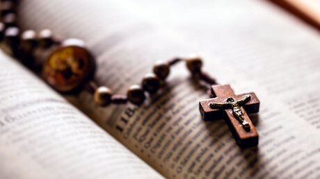 Ein Kreuz auf einem aufgeschlagenen Buch / © RHJPhtotos (shutterstock)