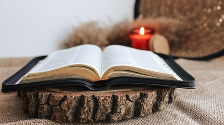 Eine aufgeschlagene Bibel und eine Kerze / © shine.graphics (shutterstock)