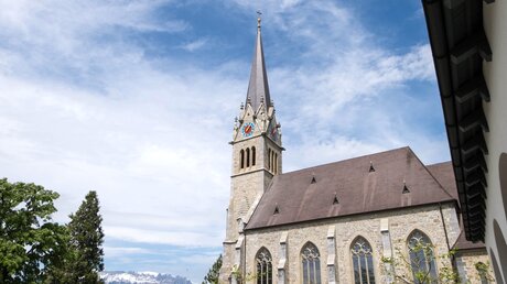 Uhrenturm der Vaduzer Kathedrale St. Florin unter der Sonne Liechtensteins. / © Yanisa C (shutterstock)
