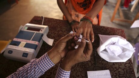 Indien: Ein Wahlhelfer bemalt den Zeigefinger einer Wählerin, damit sie ihre Stimme abgeben kann / © Manish Swarup (dpa)