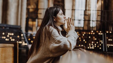 Junge Frau auf einer Kirchenbank im Gebet / © Anna Nass (shutterstock)