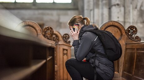 Junge Frau mit Handy in der Kirchenbank / © Harald Oppitz (KNA)
