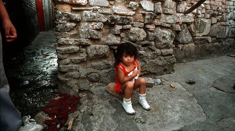 Kinderprostitution: Ein Mädchen sitzt auf einer kleinen Decke am Straßenrand / © KNA (KNA)