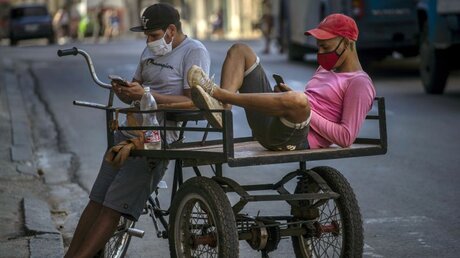 Kuba, Havanna: Menschen tragen Schutzmasken, ruhen sich auf ihrem Dreirad aus. / © Ramon Espinosa/AP (dpa)