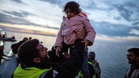 Ein Helfer mit einem Flüchtlingskind auf Lesbos / © Kay Nietfeld (dpa)